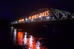 The Lower Trenton Bridge over the Delaware River, by which Amtrak and local trains cross from Trenton into Pennsylvania, is visible to automobile traffic crossing the river on U.S. Route 1. For many years, one of the letters of the sign "Trenton Makes, the World Takes" was burned out and was finally replaced in 2016 immediately before Donald Trump visited the city.